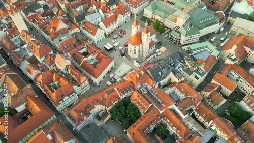 Regensburg at sunset captured from above, featuring the iconic Stone Bridge over the Danube River and the majestic twin towers of St. Peter's Cathedral glowing in warm evening light