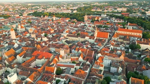 Regensburg at sunset captured from above, featuring the iconic Stone Bridge over the Danube River and the majestic twin towers of St. Peter's Cathedral glowing in warm evening light