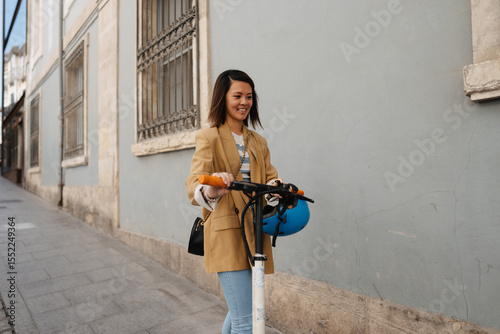 Young Asian woman driving e scooter and exploring town