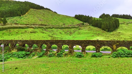 Ancient aqueduct stretching across lush green hills and volcanic landscape in São Miguel, Azores, surrounded by forest and countryside