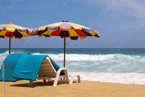 Deck chairs and parasols on a sandy beach, view to the sea waves
