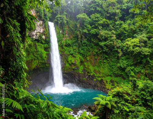 Majestic Waterfall Cascading into Turquoise Pool Surrounded by Lush Greenery