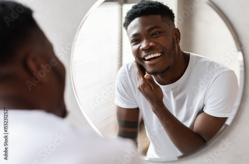 Photos Unshaven African American Guy Touching Face With Bristle On Chin Before Shaving Smiling To His Reflection In Mirror Standing In Modern Bathroom At Home