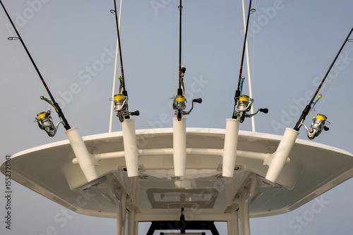 Several fishing rods and reels stored in rod holders on the top of a boat
