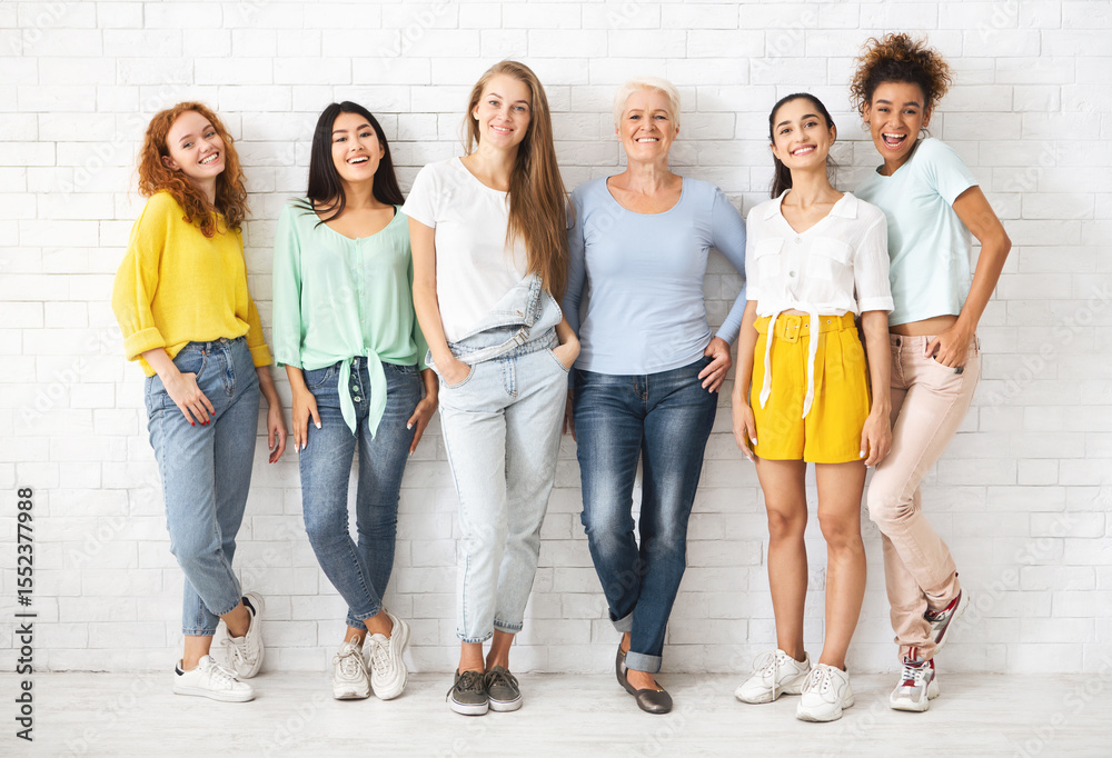 Obraz premium Female Diversity. Multiethnic Women Posing Smiling To Camera Standing Over White Brick Wall Background. Full Length
