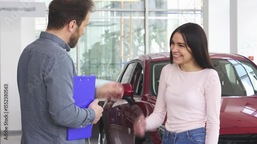 Joyful woman shaking hands with car dealer after receiving her new car keys