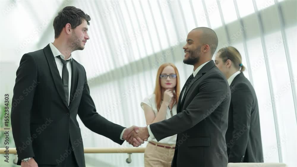 Dynamic handshake between two confident businessmen in a modern office Dynamic handshake between two confident businessmen in a modern office
