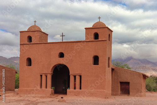 The historic Chapel of Our Lady of the Rosary of Andacollo, part of the Adobe Route in Catamarca, near Fiambala, showcases its traditional architecture within a mountainous landscape.
