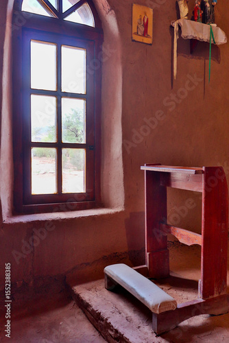A wooden kneeler and adobe-framed window capture the intimate essence of the Chapel of Our Lady of the Rosary of Andacollo, Fiambala, part of the Adobe Route