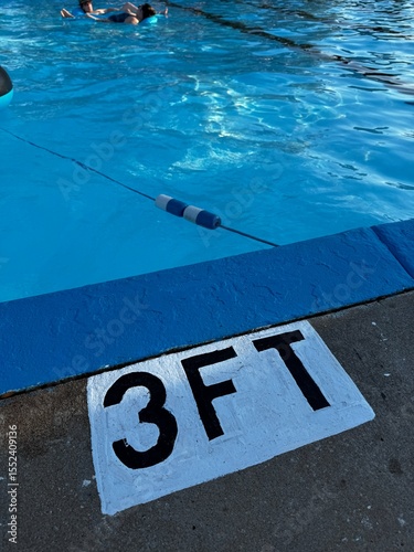 Photography swimming pool depth sign - The shallow end of a pool with a 3 foot depth sign painted on the concrete - edge of swimming pool, blue water and a safety rope