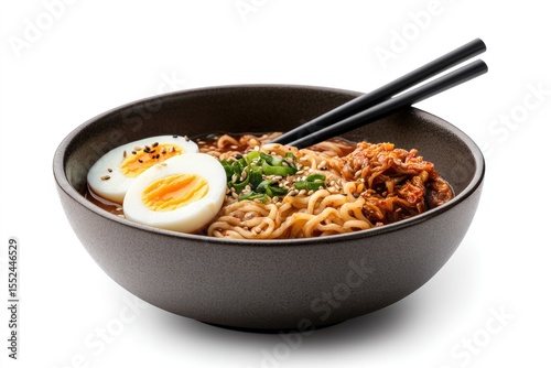 Korean instant noodles in a rustic bowl with a spicy red broth, soft-boiled egg halves floating, and a side of kimchi in a small dish