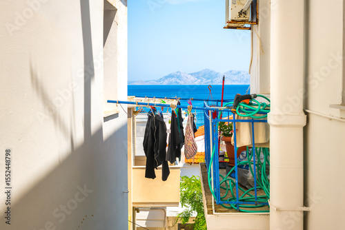 Agios Kirykos, Greece Greek island Ikaria street building sunny day with balcony clothes drying hanging and blue Aegean Sea Samos Fournoi islands