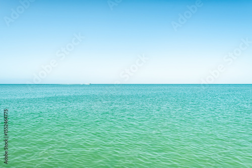 Barefoot Beach, Southwest Florida with boat riding on beautiful turquoise blue green ocean sea crystal clear water waves of Gulf of Mexico horizon