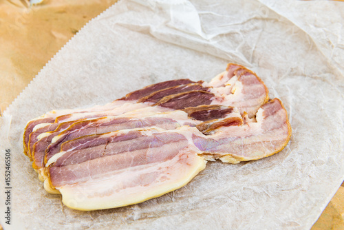 Bacon southern cured pork sliced meat fat, pasture raised food slices with hand taking holding one piece in macro closeup