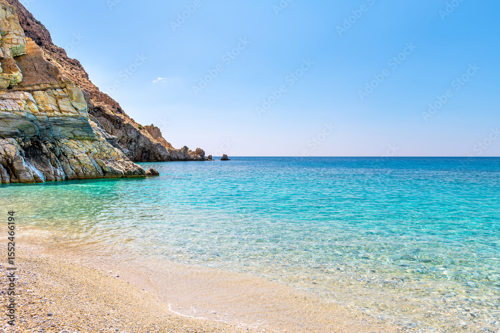 Fototapeta premium Seychelles beach in Magganitis, Ikaria island Greece by Icarian sea of crystal clear green turquoise water, rocky cliffs coast water level view