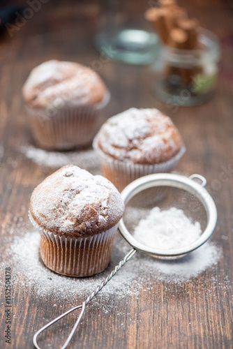 Delicious cupcakes sprinkled with powdered sugar stand on a wooden table
