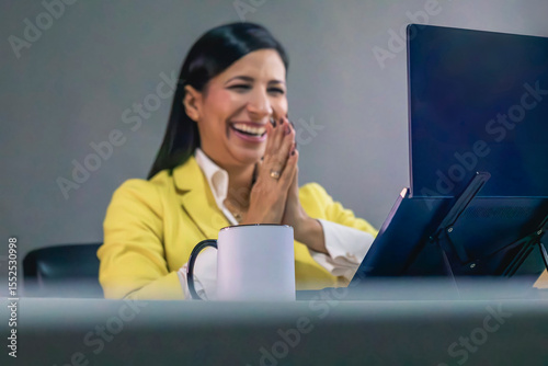 Happy latin businesswoman laughing while looking at laptop screen