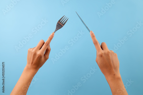 Female Hands Holding Fork And Knife Isolated On Blue Background