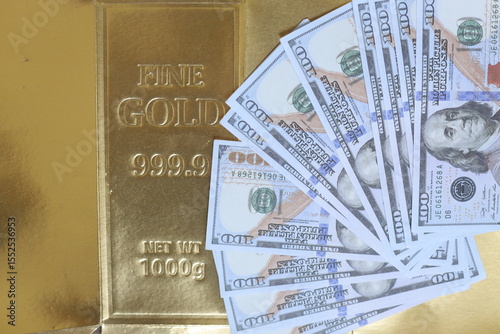 Overhead View Of Scattered US Dollar Bills On Top Of Shiny Gold Bar