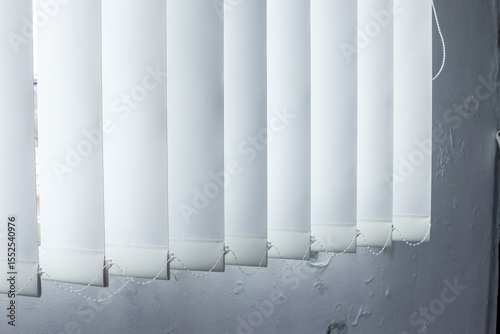 White Vertical Blinds Hang Against Textured Wall