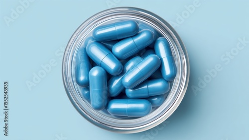 Vitamin and Supplements, medicine pills. Blue capsules in a silver bowl against a light blue background.