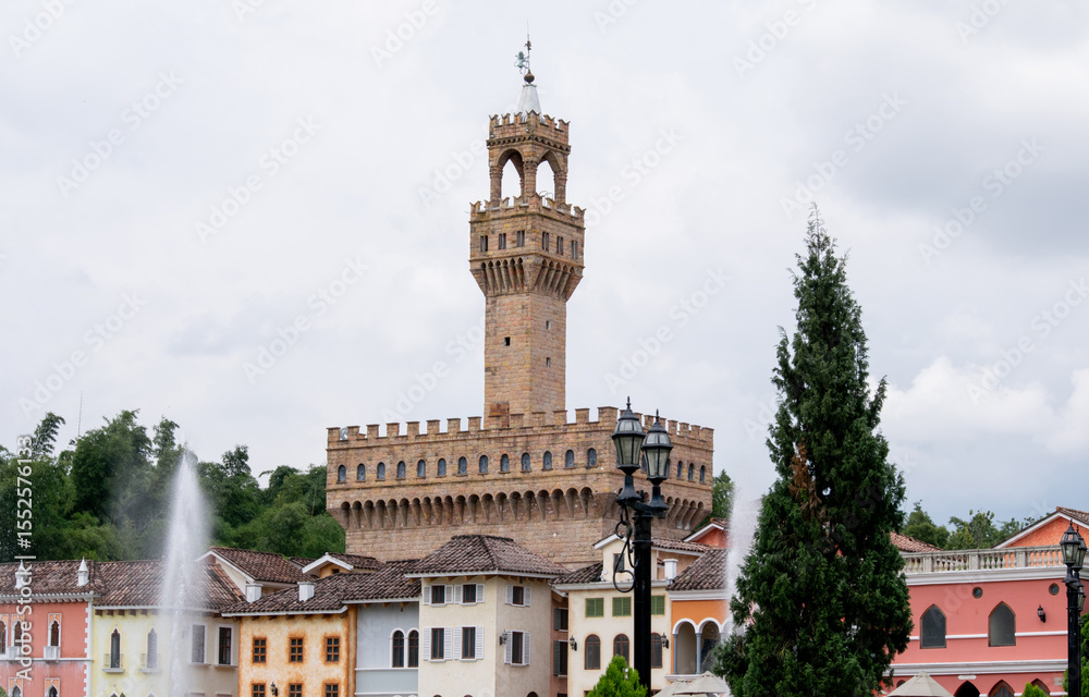 Obraz premium Photograph of a medieval castle in European style surrounded by colorful houses, fountains, and trees.