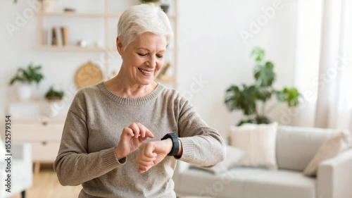 A smiling older woman with short white hair interacts with a smartwatch in a bright, cozy living room.