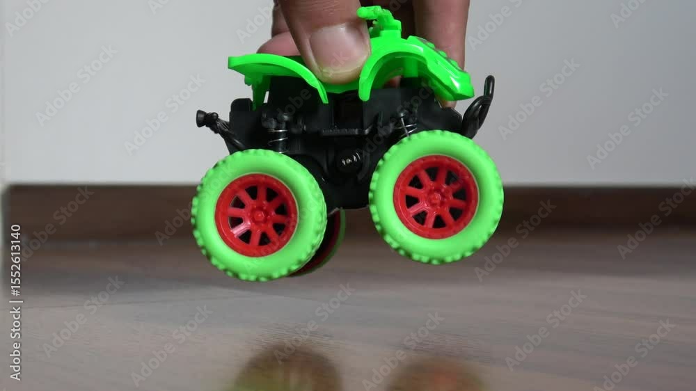 Hand playing with green go kart rubber wheel toy car close up.
