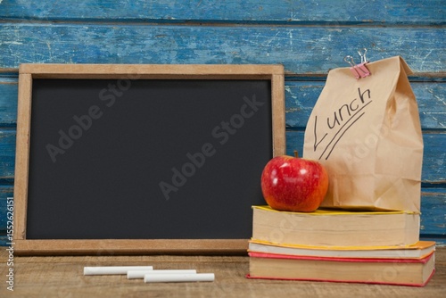 Blank blackboard with packed lunch and books