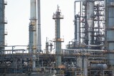 Refinery network showing flat design distillation columns, pipes, catwalks, valves under pale sky