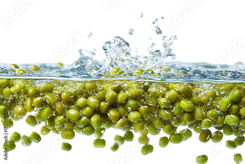 Green mung beans falling into water, splashing and floating on a transparent background. Commercial photography.