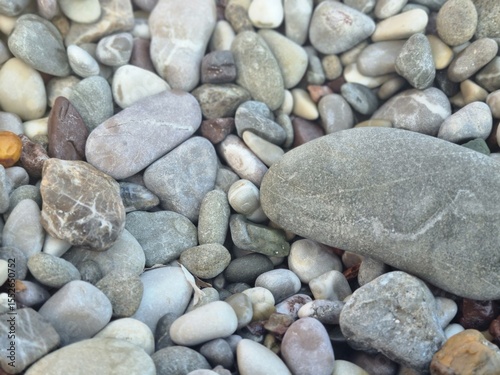 Natural smooth pebbles in various colors and sizes captured closely on the beach