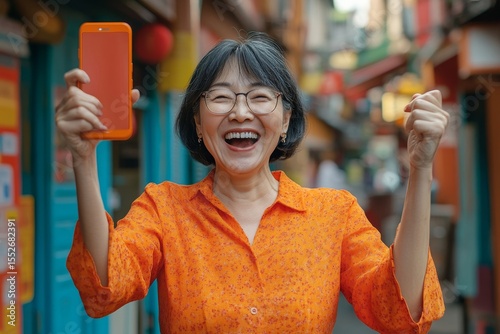 Happy Asian woman holding a smartphone, celebrating after winning a prize, feeling overjoyed by her good fortune., Generative AI