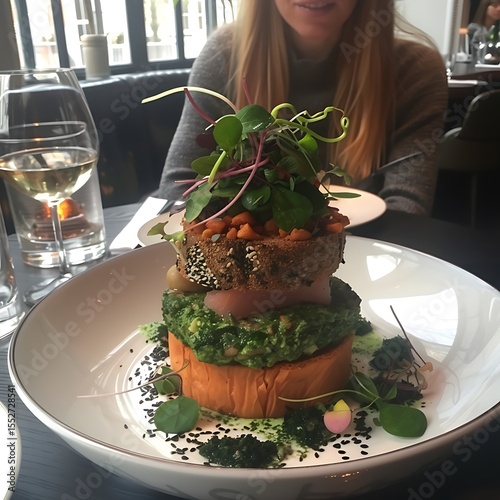 Exquisite layered dish presentation at restaurant with elegant interior background