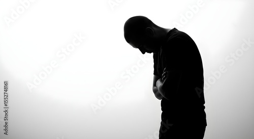 A monochrome portrait of a man in deep thought or sadness. The figure's posture shows emotional distress or quiet contemplation. Perfect for mental health content.