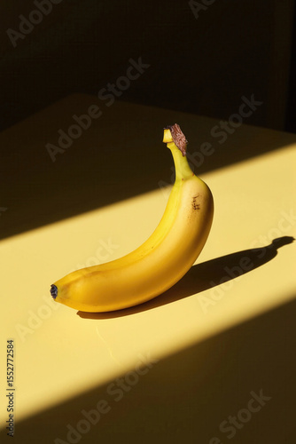 Ripe banana with bold shadow on yellow background