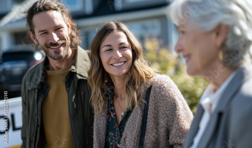 Wallpaper Mural Happy people converse outdoors by a sold real estate sign, sharing a joyful, exciting moment Torontodigital.ca