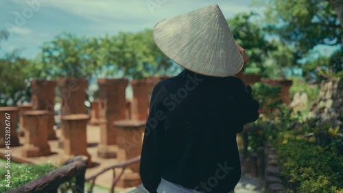 Sightseeing and travel in Asia, women in conical hat walking in park, back view. Summer vacation and weekend trip to Vietnam, exploring oriental culture, natural and historical landmarks, slow motion