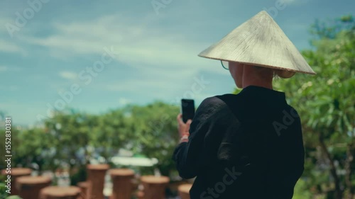 Travel in central Asia, woman tourist in conical hat taking pictures by phone. Mobile photo for social nets and memories from summer vacation, sightseeing and tourist excursion, explore asian culture