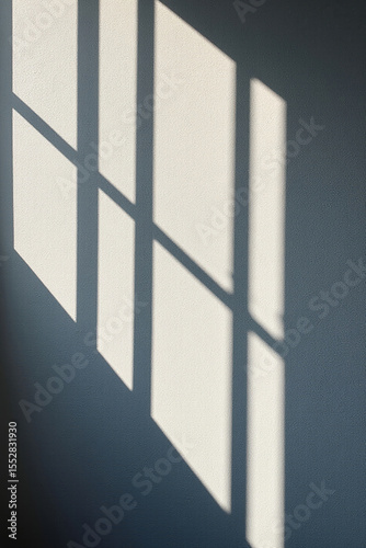 Sunlight casting geometric window shadows on a white wall