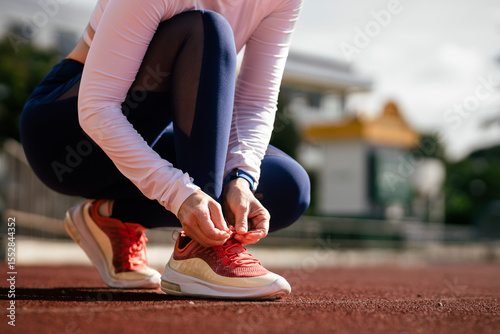 Quadro su tela Close-up of female runners tying up their shoelaces before running in the stadiu