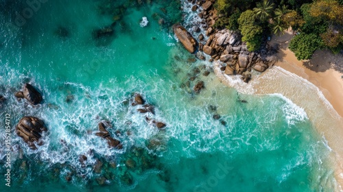 Aerial wave crashing against golden beach, green and white foam. 