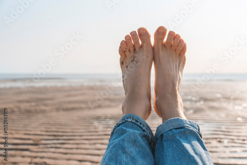 Relaxing by the beach with bare feet in the sand on a sunny day, enjoying the calm atmosphere and gentle ocean breeze