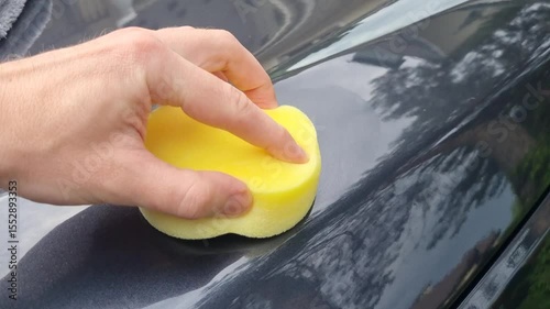 professional service man polishing and detailing on a car body, professional workman waxing a wax on a vehicle. Car wash service.