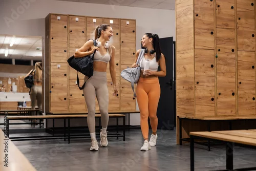 Panel kuchenny z motywem Two fit sportswomen walking into fitting room at gym and smiling at each other.