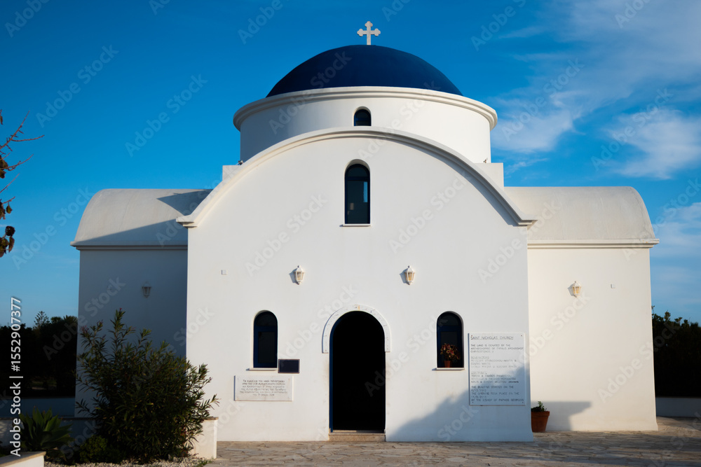 Fototapeta premium Classic Greek Orthodox church with white walls and a blue dome. Saint Nicholas Church in Paphos, Cyprus. Concept of Mediterranean culture, religious heritage