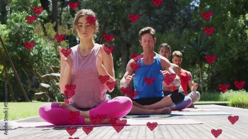Yoga practitioners sitting on wooden deck receiving floating hearts swirling hands for wellness