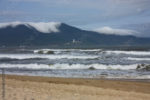 looking out  across the beach and waves in da nang in central vietnam at the lady buddha statue at linh ung pagoda on son tra peninsula on da nang bay