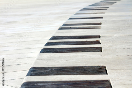 Curved concrete bench with evenly spaced dark wooden slats set into white pavement, forming a repeating geometric pattern in a sunlit urban plaza