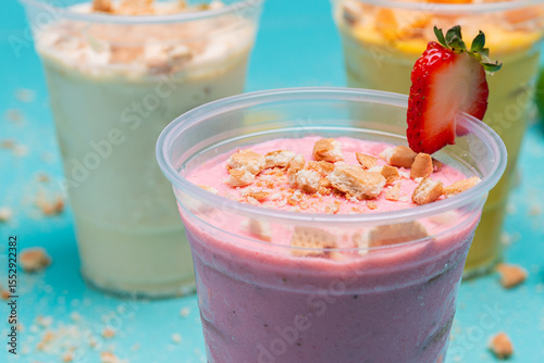 Strawberry, mango and lemon charlotte in plastic cups on light blue background photo